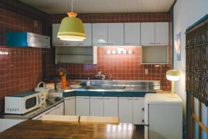 a kitchen with a sink and a microwave at ゲストハウス レトロマチカ in Sakai