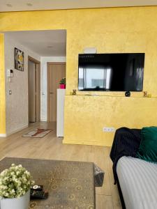 a living room with a yellow wall with a flat screen tv at Studio pas cher au parc in Mohammedia