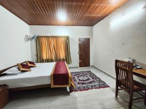 a bedroom with a bed and a desk in it at Riverwood Cottages in Kallar Vattiyar