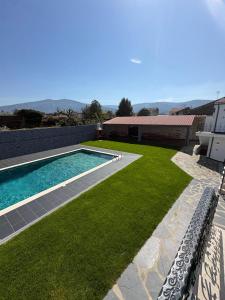 a backyard with a swimming pool and green grass at Ribeirinha in Lousã