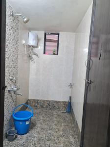 a bathroom with a bucket on the floor and a window at Umashankar Homestay in Nashik