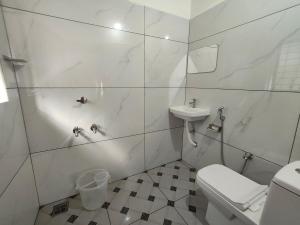 a white bathroom with a toilet and a sink at Riverwood Cottages in Kallar Vattiyar