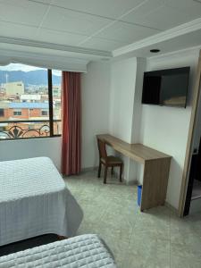 a bedroom with a bed and a desk and a window at Hotel Americas Suites in Bogotá