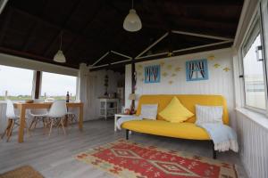 a living room with a yellow couch and a table at Casa dos Flamingos in Murtosa
