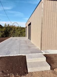 a concrete sidewalk next to a building with a door at Au loft, micro maison vue sur prairie in Rohrwiller