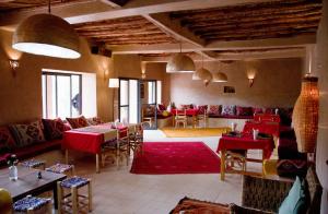 a restaurant with red tables and chairs in a room at RIAD AMAN SKOURA in Skoura