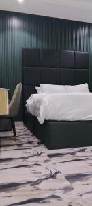 a bedroom with a large bed and a chair at Transvent Hotel and Suites in Abeokuta