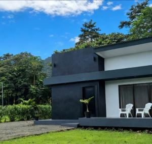 a black and white house with two white chairs at Casa del Lago #3 in Upala