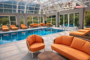 a swimming pool with orange chairs and chairs in a building at Snow Valley Resorts & Spa Manali in Manāli