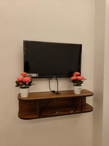 a flat screen tv sitting on a shelf with flowers at Sekar Inn in Arumuganeri