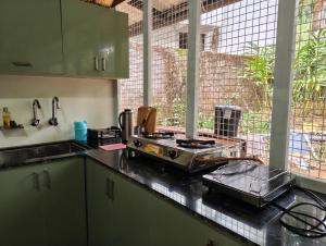 a kitchen with a counter with a stove and a window at Riverwood Cottages in Kallar Vattiyar