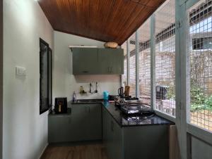 a kitchen with green cabinets and a wooden ceiling at Riverwood Cottages in Kallar Vattiyar +47 photos
