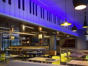 a restaurant with tables and chairs and purple lighting at ibis Styles Taubate in Taubaté