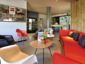 a living room with a red couch and chairs at Ibis Brussels Erasmus in Brussels