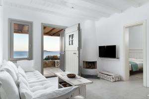 a white living room with a white couch and a fireplace at West Side Garden House in Gavrio