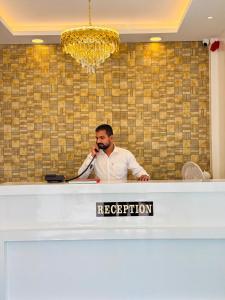a man talking on a phone at a reception desk at Hotel Aura Inn in Dehu