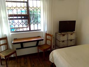 a bedroom with a bed and a desk and a tv at Adventure Cape Town 1 in Cape Town