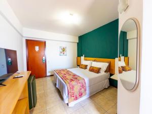 a bedroom with a bed and a desk in it at Portobello Pituba Praia in Salvador