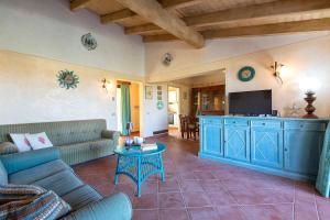a living room with a couch and a tv at Villa Belvedere Saline - Private Pool in Stintino