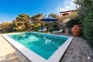 a swimming pool with an umbrella next to a house at Villa Belvedere Saline - Private Pool in Stintino