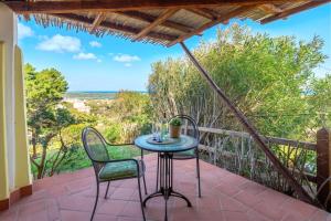 a table and chairs on a patio with a view of the ocean at Villa Belvedere Saline - Private Pool in Stintino