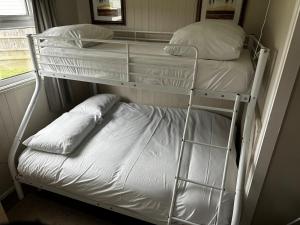 two bunk beds in a room with a bed at Seabreeze Number 74 includes swimming passes and club entry in Scratby