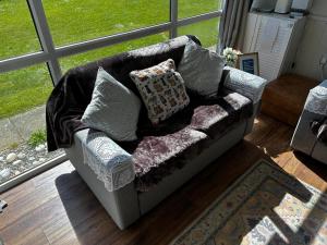 a couch with pillows on it in a living room at Seabreeze Number 74 includes swimming passes and club entry in Scratby