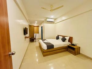 a bedroom with a bed and a tv in it at Hotel Aura Inn in Dehu +25 photos