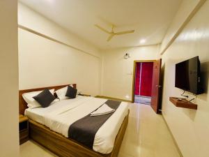 a bedroom with a bed and a flat screen tv at Hotel Aura Inn in Dehu