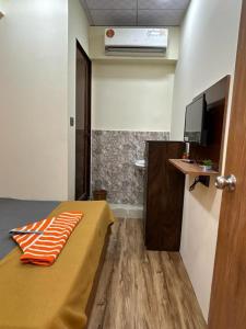 a small room with a bed and a television at hotel orange palace in Surat +14 photos