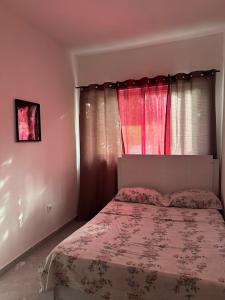a bedroom with a bed and a window with pink curtains at Quarto- Espaço Casa Mendes in Praia
