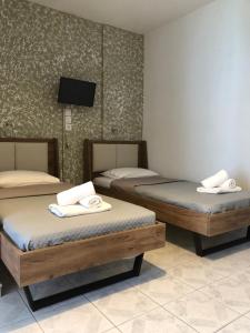 a room with two beds and a flat screen tv at Armonia Guest House in Skiathos