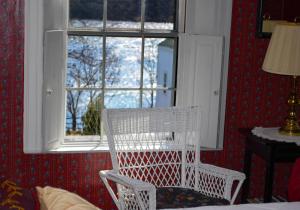a white chair sitting in front of a window at Pryor House B&B in Bath