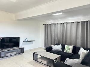 a living room with a black couch and a tv at Shine house in Somerset West