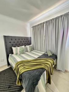 a bed in a room with a large window at Shine house in Somerset West