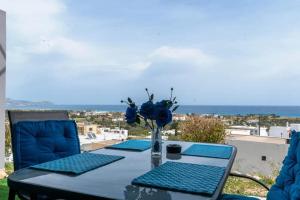 ein Tisch mit blauen Stühlen und eine Vase mit blauen Blumen in der Unterkunft Blue line in Kalathos