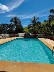 a large swimming pool with blue water at Refúgio Allamanda in Visconde De Maua +22 photos