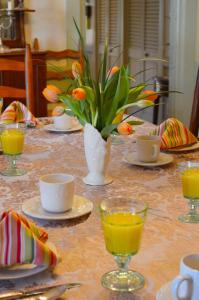 a table with a vase of flowers and orange juice at Pryor House B&B in Bath
