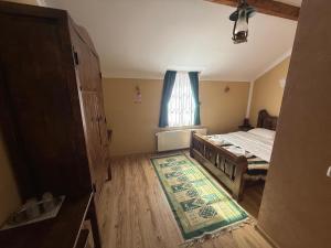 a bedroom with a bed and a window and a rug at HANUL TENTEA in Săcel +15 photos