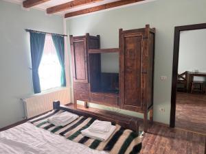 a bedroom with a bed and a wooden cabinet at HANUL TENTEA in Săcel
