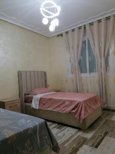 a bedroom with two beds and a chandelier at Résidences nour nador in Nador