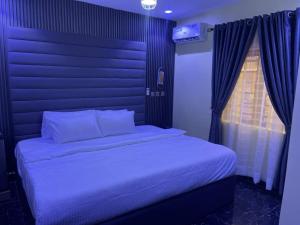 a bedroom with a bed with a blue head board at Transvent Hotel And Suites in Abeokuta