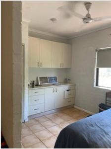 a kitchen with white cabinets and a tile floor at Pearlers Lodge in Broome