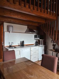 a kitchen with a table and chairs in a room at Le Mirasol Appart-hôtel in Enveitg