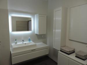 a white bathroom with a sink and a mirror at Ferienwohnung Anita in Rust +77 photos