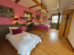 a bedroom with two beds and pink walls at Casa do Plátano in Cinco Ribeiras