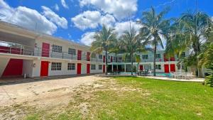 a building with red and white doors and palm trees at HOTEL REAL UCUM in Ocum