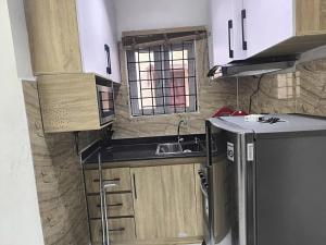 a small kitchen with wooden cabinets and a sink at Cosmo Haven Suites - Self Contained Apartment in Ibadan
