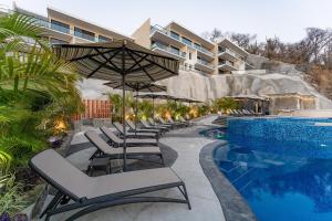 a row of lounge chairs next to a swimming pool at 3075 - Paradise Cove 3A Cacalutilla in Tangolunda