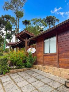 a home with a wooden house with a patio at Refúgio Allamanda in Visconde De Maua